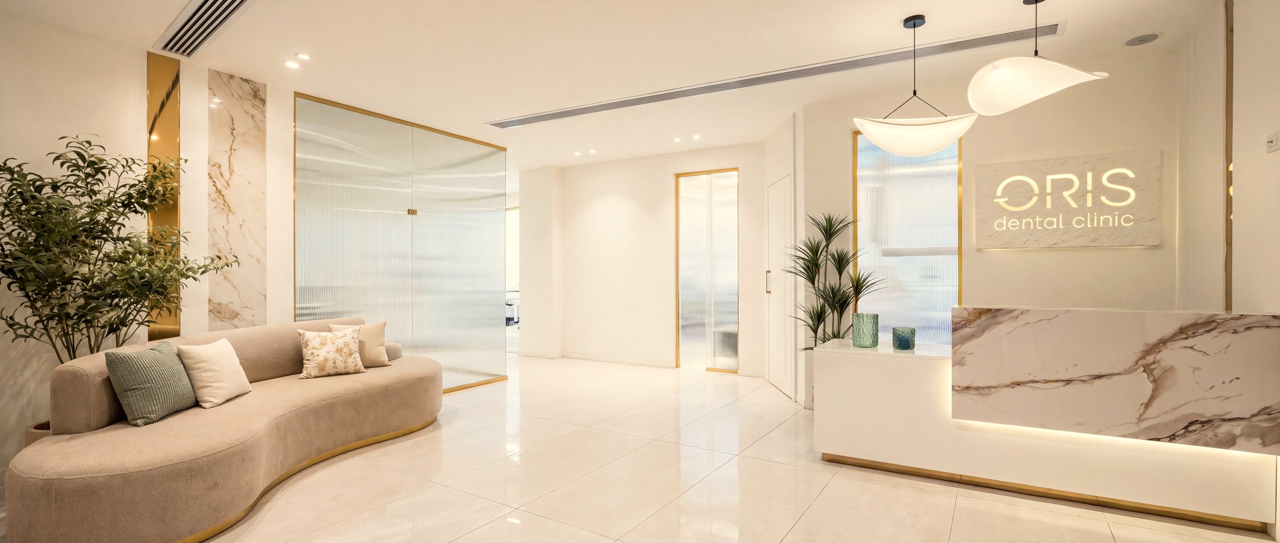 Reception and waiting lounge at ORIS Dental Clinic: marble reception desk, backlit ORIS sign, curved sofa and fluted glass
